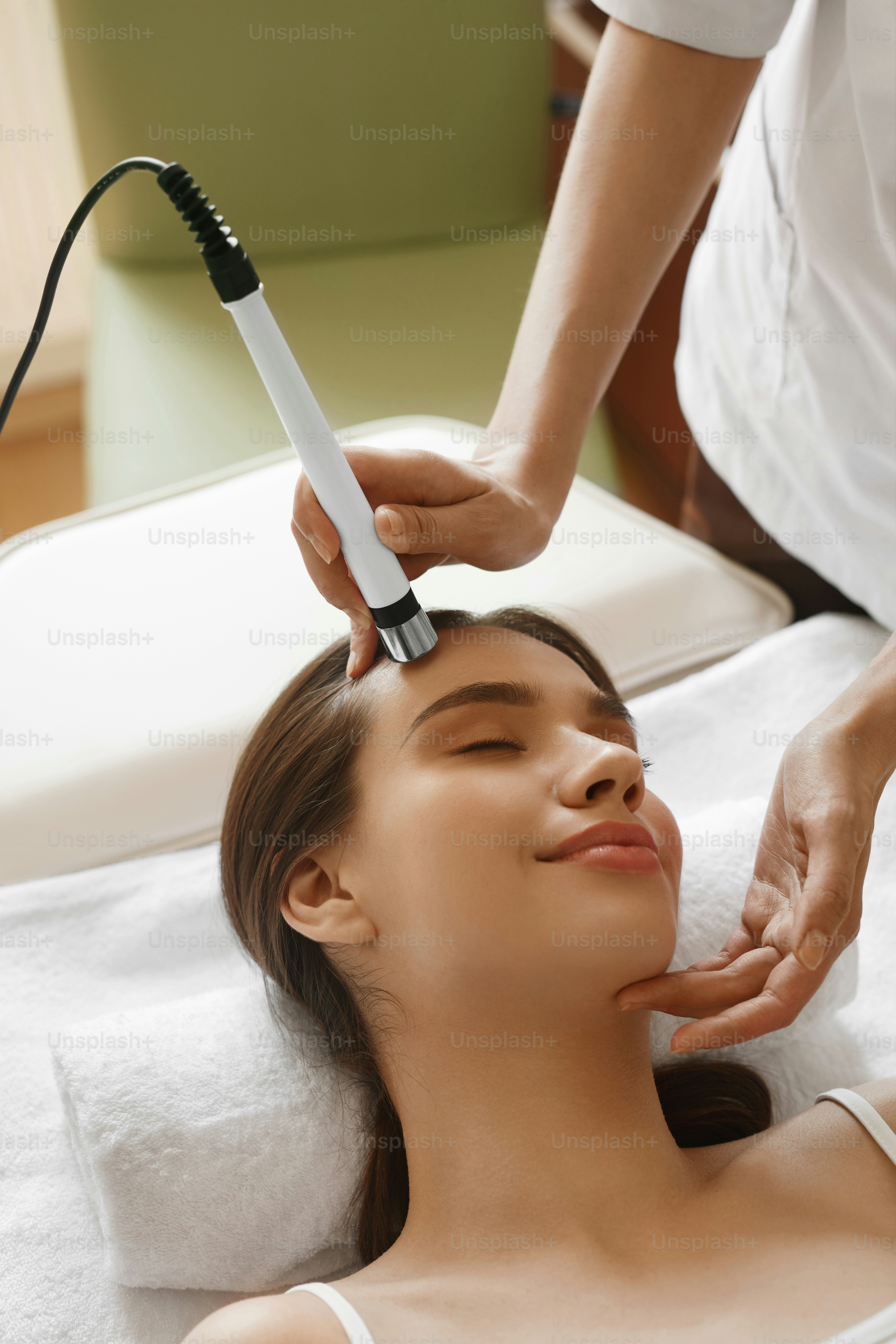 A person receiving a facial treatment with a handheld device on their forehead